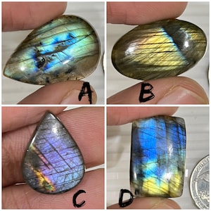 May include: Four polished labradorite gemstones in various shapes. The stones display iridescent flashes of blue, green, yellow, and purple. Each stone is held by a person's fingers, showcasing the natural beauty and color variations of the gemstones.