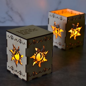 May include: Two wooden candle holders with a sun design and the quote "The dream that was with me all the time was with me all the time because..."  The candle holders are lit and glowing.
