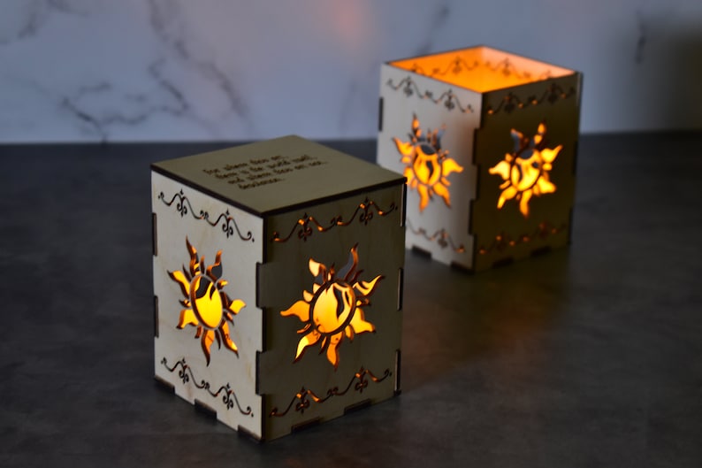 May include: Two wooden candle holders with a sun design and the quote "The dream that was with me all the time was with me all the time because..."  The candle holders are lit and glowing.