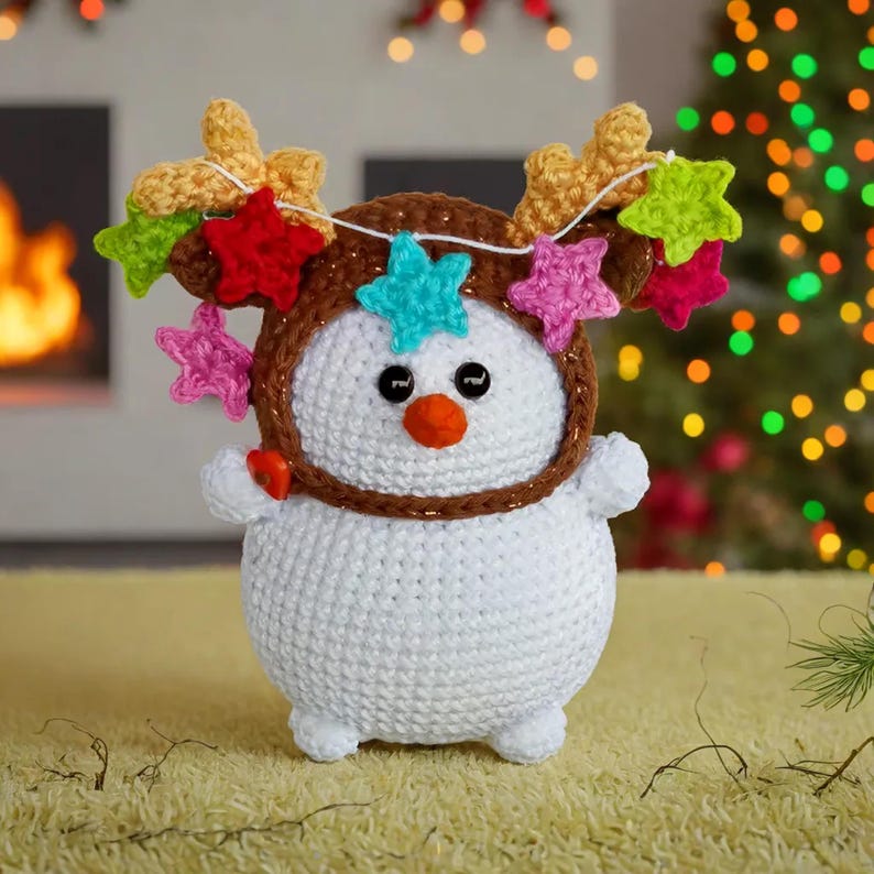 an amigurumi snowman wearing a reindeer hat with stars on it