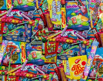 May include: A colorful assortment of individually wrapped candies and lollipops. The candies are in a variety of shapes, sizes, and colors, including red, blue, green, yellow, and orange. Some of the candies have text on them, such as "Fizz Wiz" and "Dip Dab".
