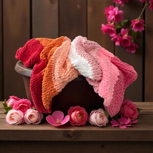 Peut inclure: Plusieurs couvertures douces aux couleurs vives, rouge, orange, rose et blanc, drap&eacute;es sur un r&eacute;cipient marron fonc&eacute;. Des roses et des fleurs roses entourent les couvertures, cr&eacute;ant une ambiance chaleureuse et accueillante.