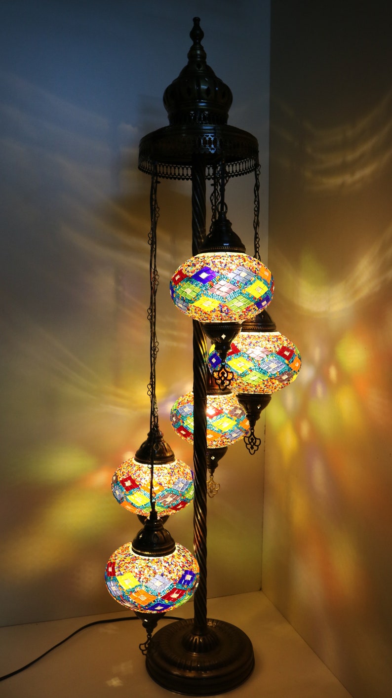 May include: A floor lamp with a twisted metal base and four colorful mosaic glass globes. The globes are lit and cast a warm glow.
