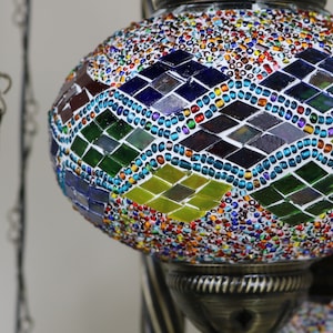 May include: A colorful mosaic glass globe pendant light fixture with a diamond pattern. The globe is made of small, colorful glass tiles and beads.