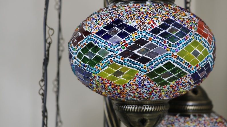 May include: A colorful mosaic glass globe pendant light fixture with a diamond pattern. The globe is made of small, colorful glass tiles and beads.
