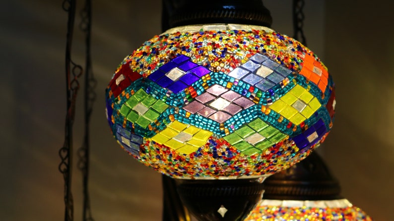 May include: A colorful mosaic glass lampshade with a geometric pattern in shades of blue, green, yellow, and purple. The lampshade is round and has a metallic base.