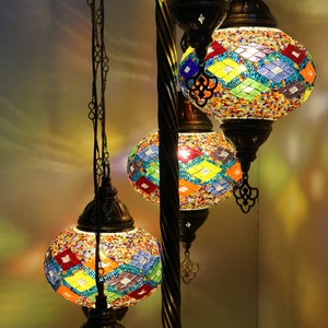 May include: A floor lamp with five colorful mosaic glass globes. The globes are in shades of blue, green, yellow, red, and orange. The lamp has a black metal base and a twisted metal pole.