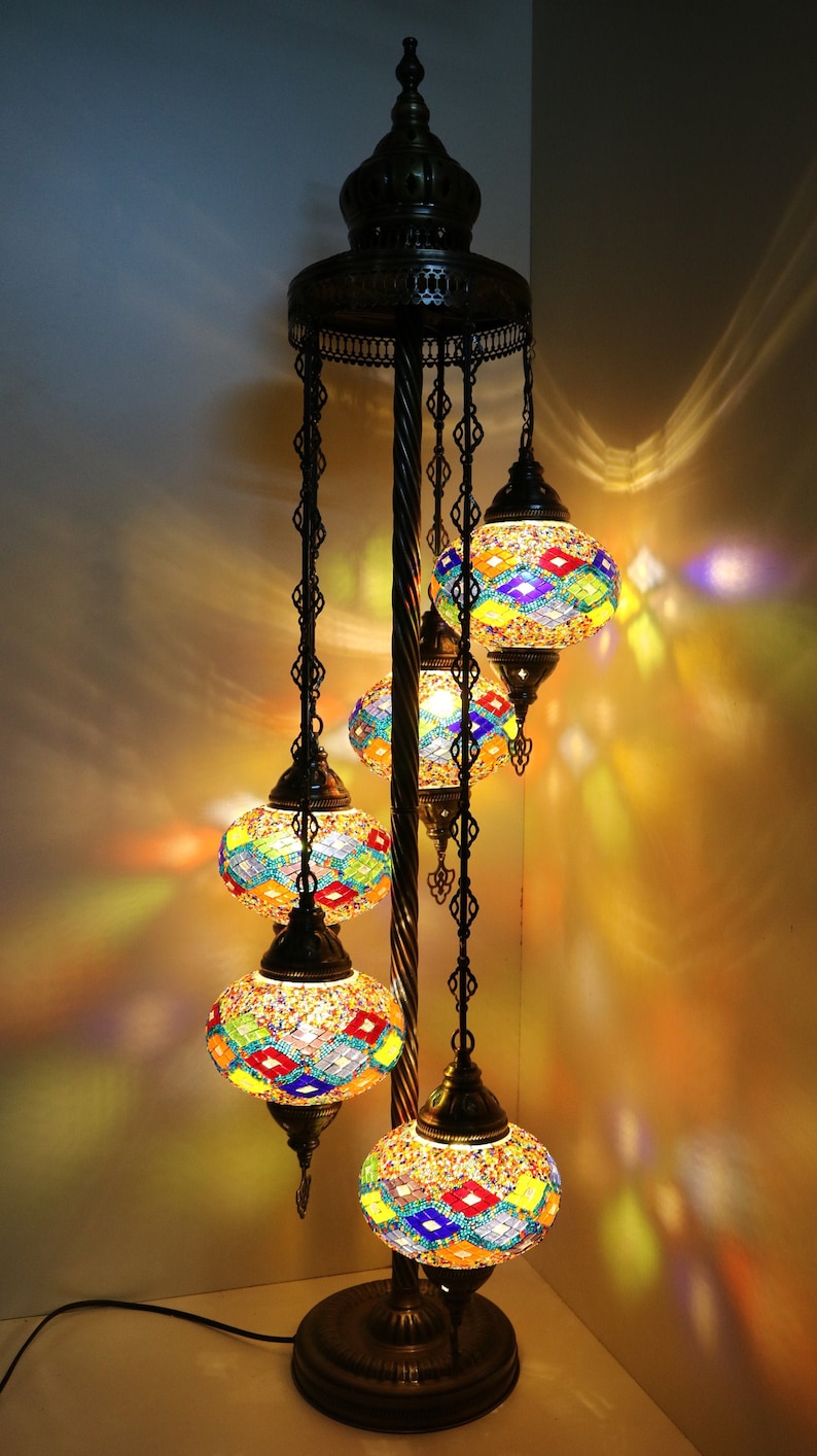 May include: A floor lamp with a black metal base and five colorful mosaic glass globes. The globes are suspended from chains and have a variety of geometric patterns.