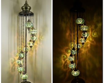 May include: A spiral floor lamp with a brass finish and nine green and white mosaic glass globes. The lamp is lit and casting a warm glow.