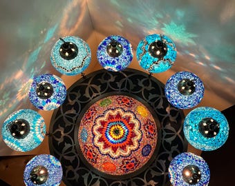 May include: A ceiling light fixture with a central dome surrounded by 12 smaller globes. The dome is made of colorful mosaic tiles and the globes are made of blue mosaic tiles.