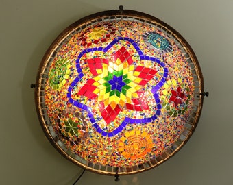 May include: A round, colorful mosaic ceiling light fixture with a star-shaped design in the center. The mosaic is made of small, colorful glass tiles.