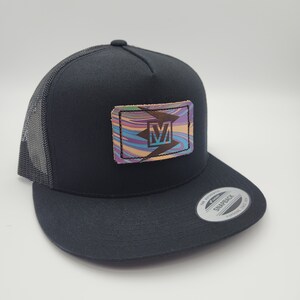 May include: Black trucker hat with a black and white logo on a leather patch with a colorful swirl pattern. The logo is a stylized "V" with a lightning bolt.