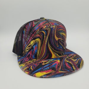 May include: A black and white trucker hat with a colourful abstract swirl pattern in red, yellow, and blue.
