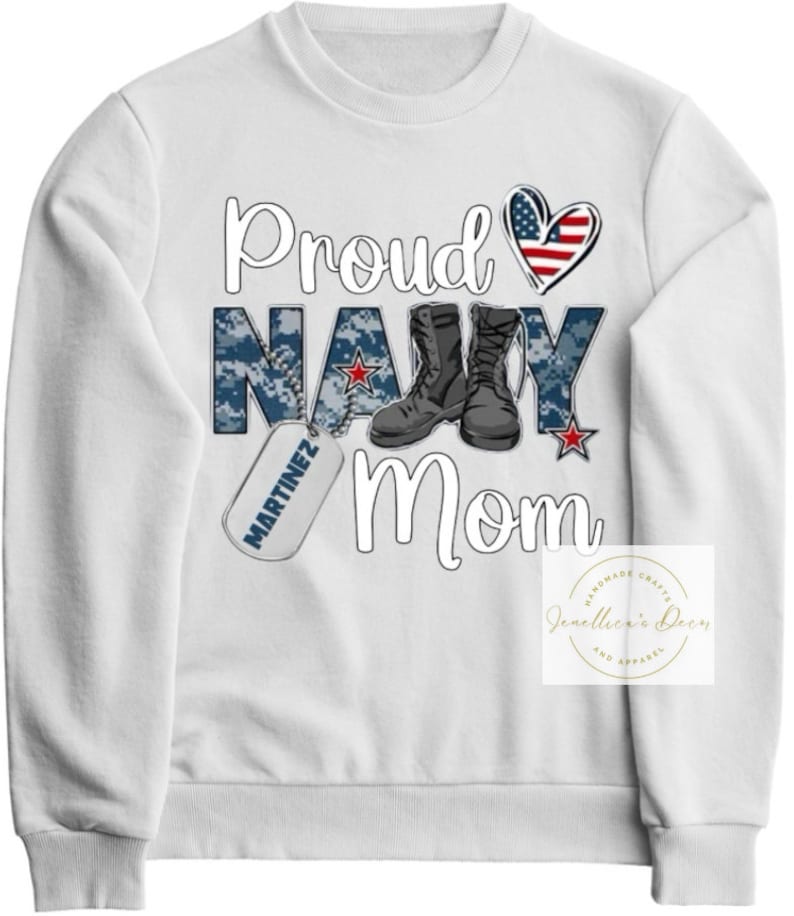May include: White sweatshirt with the text "Proud Navy Mom" in black. The text is surrounded by a camouflage pattern, a heart with the American flag, a pair of black boots, and a dog tag with the text "MARTINEZ" in black.