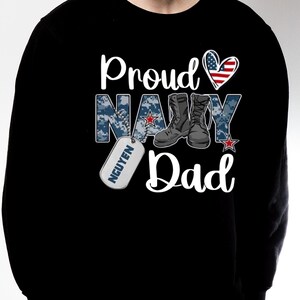 May include: Black sweatshirt with a white graphic that says "Proud Navy Dad" with a red, white, and blue heart, camouflage pattern, boots, and a dog tag that says "NGUYEN".