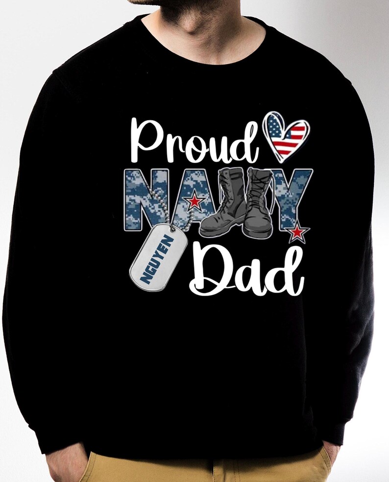 May include: Black sweatshirt with a white graphic that says "Proud Navy Dad" with a red, white, and blue heart, camouflage pattern, boots, and a dog tag that says "NGUYEN".