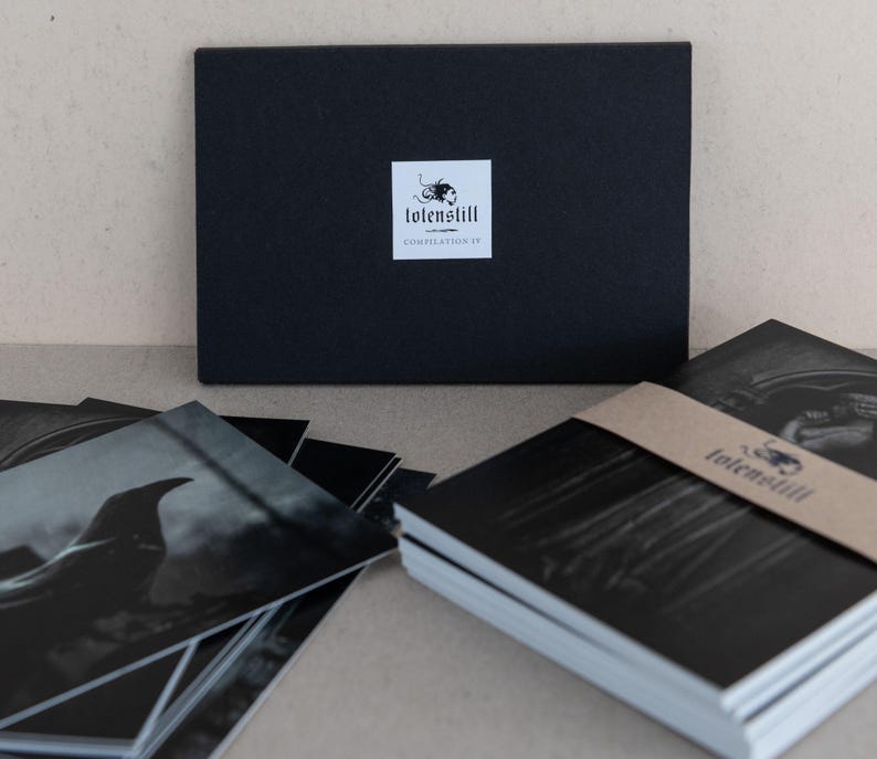 May include: A stack of black and white photo cards with a black envelope. The envelope has a white label with the text "tolen still" and "compilation 19".