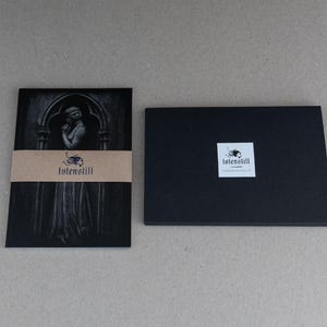May include: Black and white image of a woman in a gothic setting. The image is printed on a card with a brown paper label that reads "totenstill".