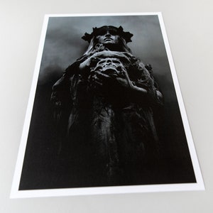 May include: A black and white photograph of a statue of a woman wearing a crown and holding a skull. The statue is in a dark, shadowy setting.