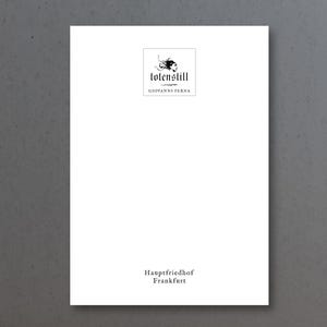 May include: A white card with black text and a logo. The logo is a black and white illustration of a woman's head with a flower in her hair. The text reads "totenstill" and "GIOVANNI PERNA". Below the logo, the text reads "Hauptfriedhof Frankfurt".