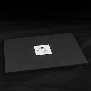 May include: Black box with a white label that says "tolenstill collection 18" and has a black and white logo of a stylized scorpion.