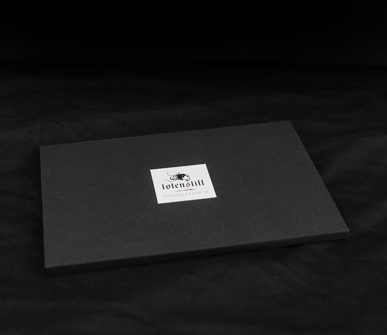 May include: Black box with a white label that says "tolenstill collection 18" and has a black and white logo of a stylized scorpion.