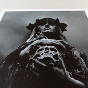 May include: A black and white photograph of a stone sculpture of a woman wearing a crown of thorns and holding a skull in her hands.