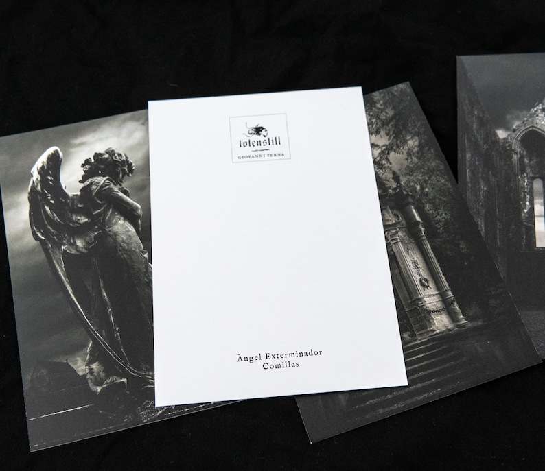 May include: A black and white postcard with a photo of an angel statue in a cemetery. The text on the postcard reads "Angel Exterminador Comillas" and "totenStill Giovanni Verna".
