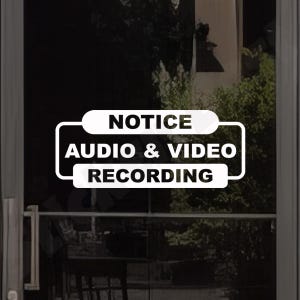 May include: A rectangular white vinyl decal for glass surfaces featuring rounded corners and a bold black border. The text is printed in a clean, sans-serif font and reads NOTICE AUDIO & VIDEO RECORDING in three stacked lines of text.