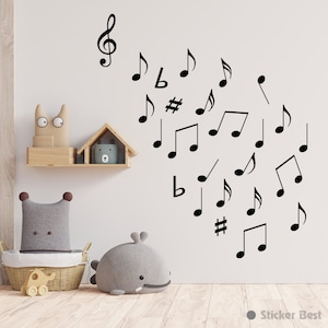 May include: A white wall with black musical notes and a treble clef sticker. The wall is decorated with a wooden shelf with a stuffed animal and a small house-shaped object.