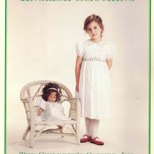 May include: A book cover with the text "ENGLISH SMOCKING" in green. A young girl in a white dress and red shoes stands next to a doll in a white dress sitting in a white wicker chair. The text "THE CHILDREN'S CORNER, INC." is below.