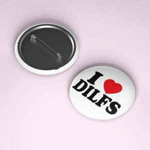 May include: White button with black text that reads "I love DILFS" with a red heart.
