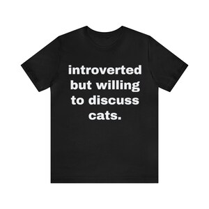 May include: Black t-shirt with white text that reads "introverted but willing to discuss cats."