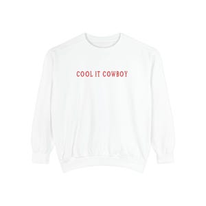 May include: White long-sleeved sweatshirt with the text "COOL IT COWBOY" printed in red on the front.