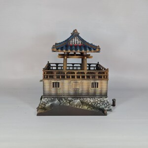 K&ouml;nnte beinhalten: Miniaturmodell einer traditionellen asiatischen Pagode. Die Struktur hat ein blaues Ziegeldach, Holzs&auml;ulen und eine detaillierte Fassade. Der Sockel besteht aus Stein, und das Design ist aufwendig.