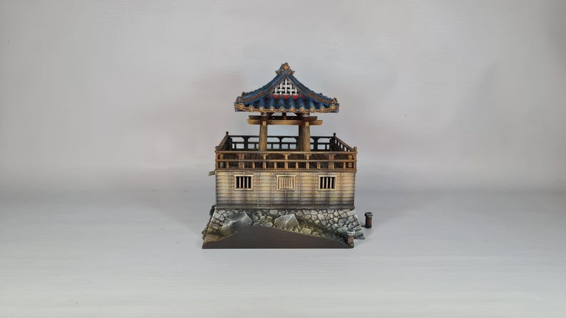 K&ouml;nnte beinhalten: Miniaturmodell einer traditionellen asiatischen Pagode. Die Struktur hat ein blaues Ziegeldach, Holzs&auml;ulen und eine detaillierte Fassade. Der Sockel besteht aus Stein, und das Design ist aufwendig.