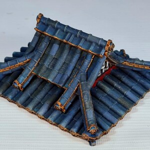 K&ouml;nnte beinhalten: Ein Miniaturdach in Blau und Gold, wahrscheinlich f&uuml;r ein Modell oder Diorama. Die Dachziegel sind tiefblau mit subtilen Variationen, und die Kanten sind mit Gold akzentuiert. Das Design deutet auf einen asiatischen Architekturstil hin.