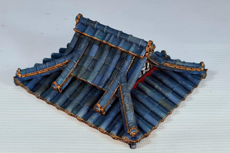 K&ouml;nnte beinhalten: Ein Miniaturdach in Blau und Gold, wahrscheinlich f&uuml;r ein Modell oder Diorama. Die Dachziegel sind tiefblau mit subtilen Variationen, und die Kanten sind mit Gold akzentuiert. Das Design deutet auf einen asiatischen Architekturstil hin.