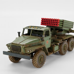 May include: A detailed model of a military truck with multiple rocket launchers. The truck is painted in olive green with a red star emblem. The rocket launchers have red tips. The tires are large and rugged.