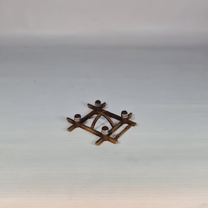 K&ouml;nnte beinhalten: Ein kleiner, quadratischer Kerzenhalter aus Holz mit vier Metallkerzenschalen. Der Halter ist aus dunkelbraunem Holz gefertigt und hat ein einfaches, geometrisches Design. Der Kerzenhalter ist ca. 10 cm breit und 10 cm lang.