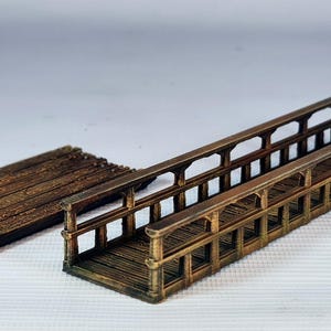 Peut inclure: Un modèle de pont miniature en bois comprenant une longue passerelle avec des garde-corps des deux côtés et une section rectangulaire séparée en planches de bois. La structure est peinte dans des tons bruns avec des textures de grain.
