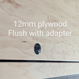 Może przedstawiać: Zbliżenie jasnej powierzchni ze sklejki z czarnym przyciskiem i tekstem "12mm plywood Flush with adapter". Widoczne usłojenie drewna. Przycisk jest wyśrodkowany na panelu drewnianym.