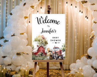 May include: A welcome sign for Jennifer's baby shower, featuring a watercolor illustration of a red barn and tractor. The sign is displayed on a wooden easel, surrounded by white balloons and decorative lights. The text reads "Welcome to Jennifer's Baby Shower Oct 16 2024."