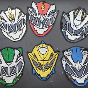 May include: Six embroidered patches with animal face designs in various colours. The patches feature white, red, green, yellow, and blue designs with detailed stitching. Each patch has a unique geometric pattern and a dark outline.