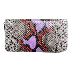 Peut inclure: Un portefeuille rectangulaire avec un motif peau de serpent dans les tons de gris, de rouge et de violet. Le portefeuille a une fermeture éclair et une surface texturée. Le design présente un mélange de couleurs neutres et vives.