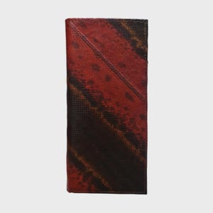 May include: A vertical, rectangular wallet with a textured, patterned surface. The colour gradient transitions from deep red at the top to a dark brown at the bottom. The wallet's design features diagonal lines and subtle colour variations.