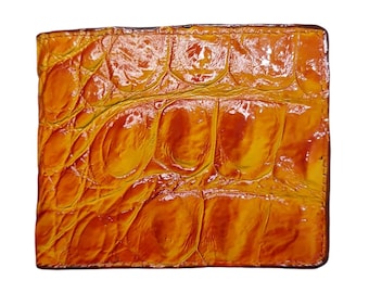 Puede incluir: Una cartera de piel de cocodrilo amarilla y naranja. La cartera tiene una superficie texturizada y un acabado brillante.