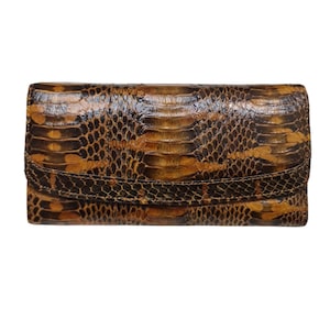 May include: A brown and black snakeskin wallet with a flap closure. The wallet has a textured surface and a natural pattern. The wallet is rectangular and appears to be made of leather.