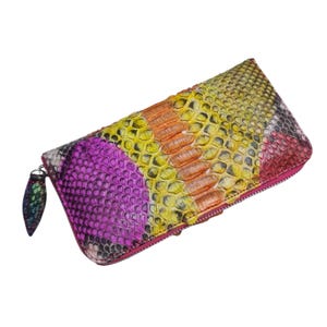 Op de afbeelding: Een rechthoekige clutch met een slangenprint. De clutch heeft een ritssluiting en een treklipje. De kleuren zijn roze, geel, oranje en grijs. De clutch is ongeveer 25 cm lang.