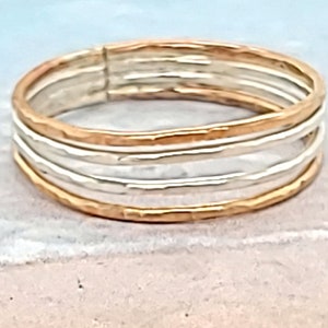 May include: A gold and silver ring with a hammered texture. The ring is made of multiple bands stacked on top of each other.
